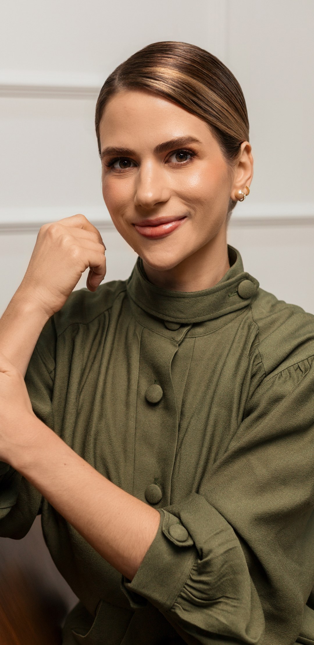 Retrato da Dra. Luisa de Angeli, dermatologista, vestindo blazer verde-oliva, sorrindo em ambiente claro